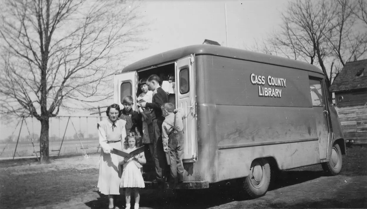 CED Scrapbook Miss Gabrielle Martens and book mobile with young patrons crica 1949
